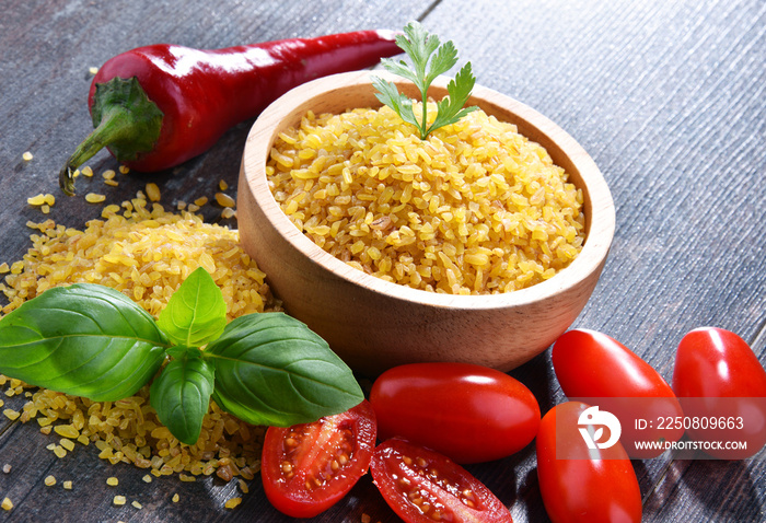 Bowl of uncooked bulgur on wooden table