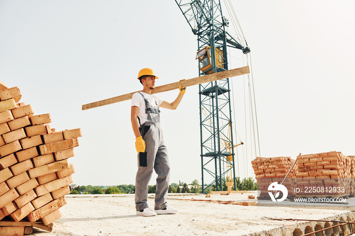 用木板。穿着制服的年轻建筑工人在未完工的建筑前忙碌