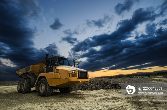 Großer Muldenkipper auf Baustelle mit düsteren Abendwolken