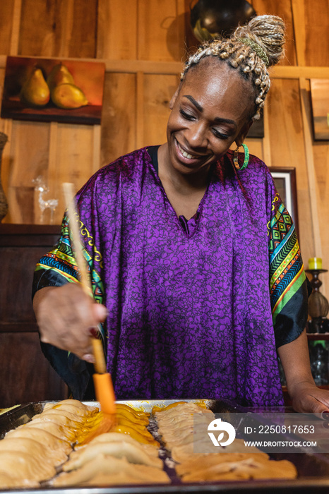 Imagen vertical de una mujer afrocaribeña muy sonriente en el interior de su casa preparando algunos