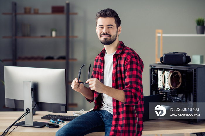 Portrait of attractive clever cheerful skilled guy technician sitting on table start-up project dire