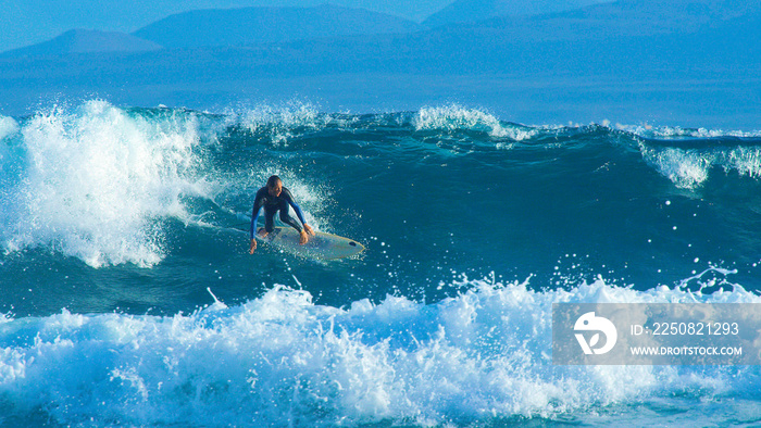 Big barrel wave pushes the young surfer towards the coastline of Canary Islands.