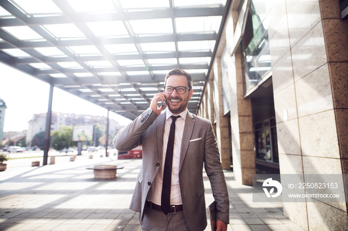 Smiling young businessman walking with confidence to a new business meeting.Talking over cell phone 