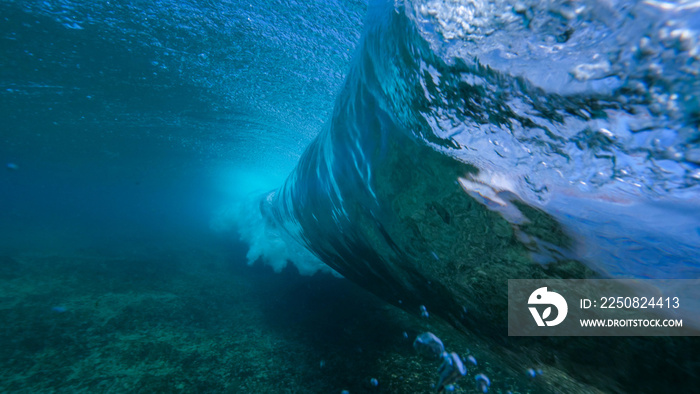 UNDERWATER: Large deep blue ocean waves breaking and splashing over the camera.