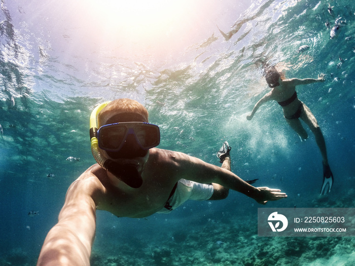 Making selfie underwater. Couple snorkeling in deep blue sea.