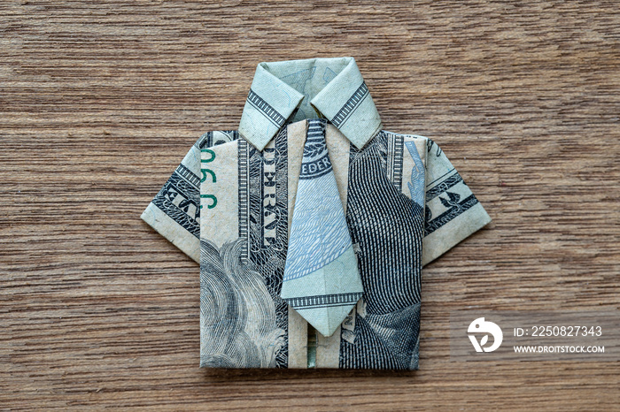 Origami shirt made of dollar banknote on wooden background. Closeup. Dollar bill T-shirt