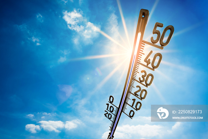 Hot summer or heat wave background, bright sun on blue sky with thermometer