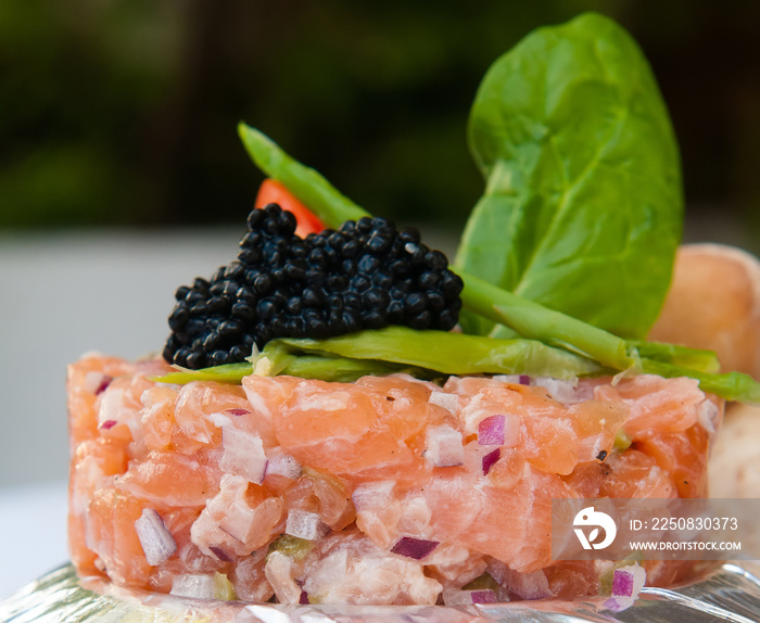 Salmon tartare or tartar with red onion, avocado, arugula and caviar