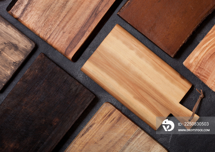 Vintage wooden cutting boards different shapes on top of black stone kitchen stone background. Top v