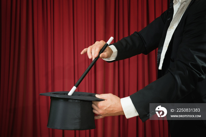 Magician with top hat and magic wand performing on stage