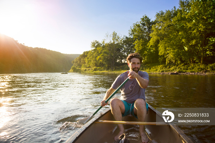 Young man canoeing in river