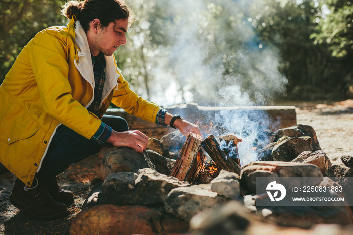 Man setting up a campfire in  a forest