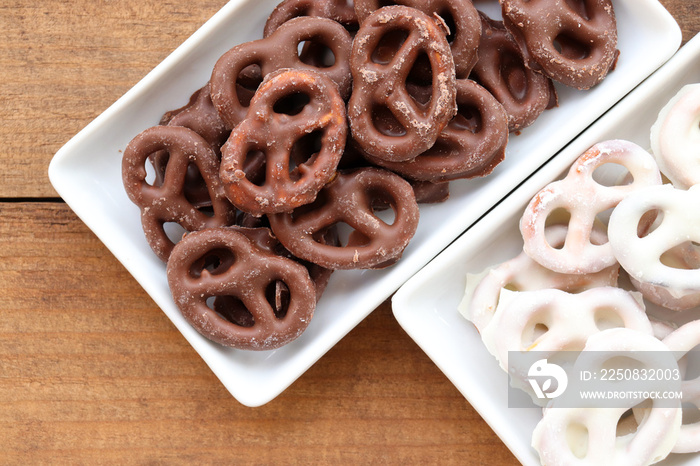 White and dark salted chocolate covered mini pretzels in a bowl on wood table. Homemade assorted min