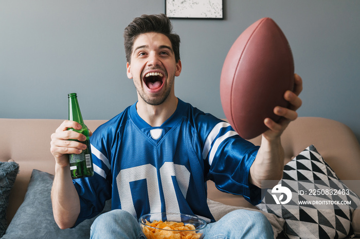 Photo of man screaming and drinking beer while watching sports match