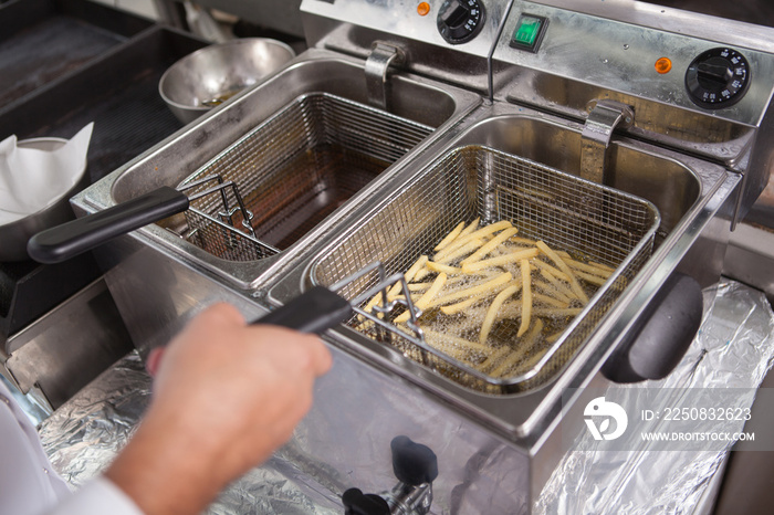 Cropped shot of a professional chef preparing french fries in hot oil fryer