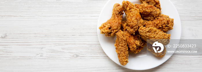 Chicken wings on a round white plate over white wooden table, top view. Flat-lay, overhead. Space fo