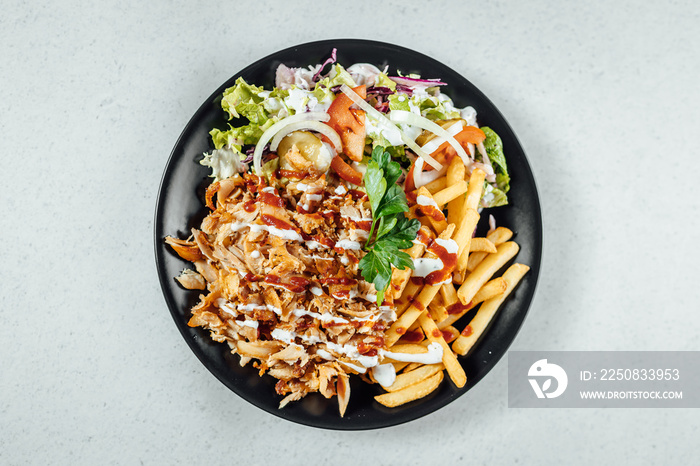 Doner Kebab on plate with vegetables fries and souce, grilled meat on plate