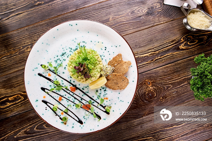 Restaurant served avocado salad on plate, top view. Salad with herring in belgian style, avocado and