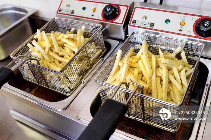 Crispy golden potato chips draining on a fryer