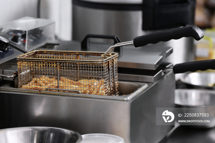 French fries in deep fryer on kitchen