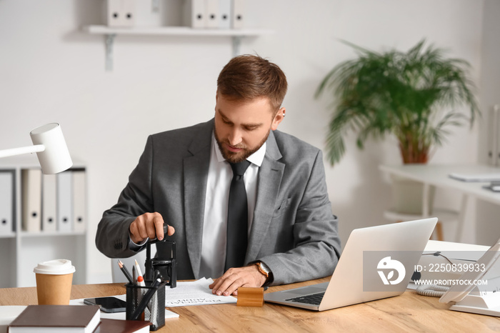 Male notary public attaching seal to document in office