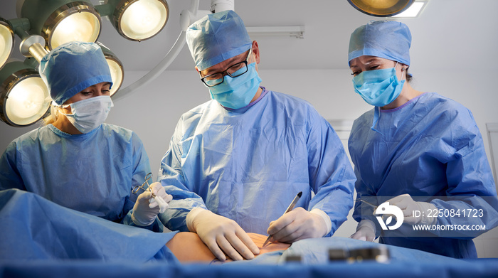 身穿蓝色手术服的医生在病人躺在手术台上进行美容手术。