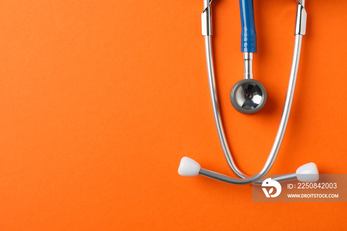 Stethoscope on orange background, space for text. Healthcare