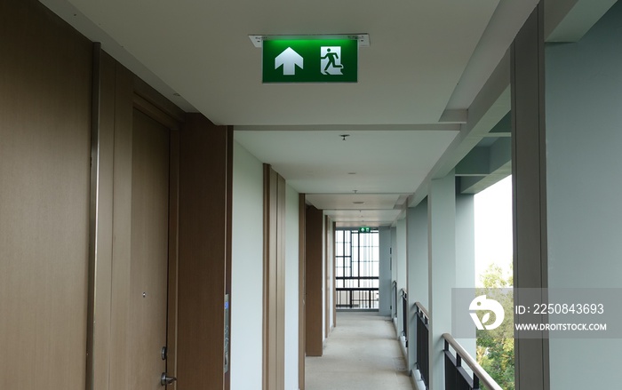 紧急消防出口指示牌指向建筑物门口，绿色且狭窄。