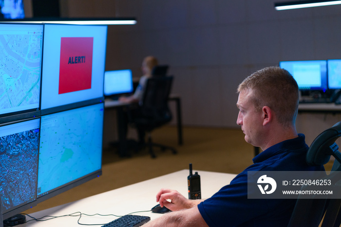 在安全控制室内，官员在接收警报信号时监控多个屏幕。