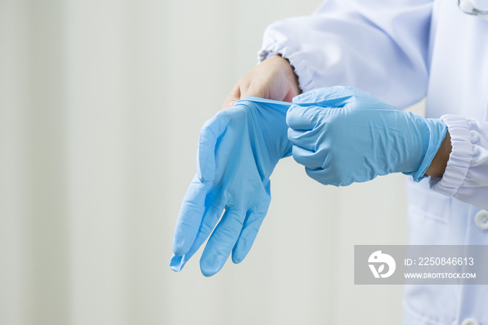 女医生在白墙背景上戴蓝色乳胶医用手套。外科医生之前戴手套