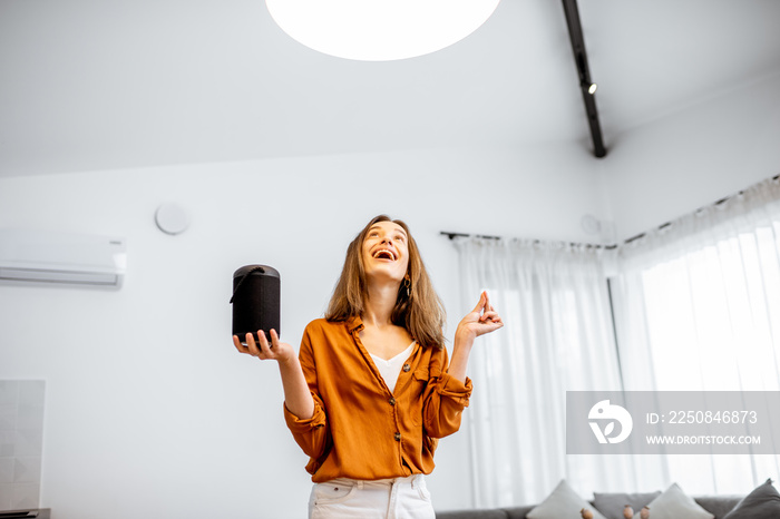 Happy woman controlling home light with a smart speaker in the living room. Concept of a smart home 