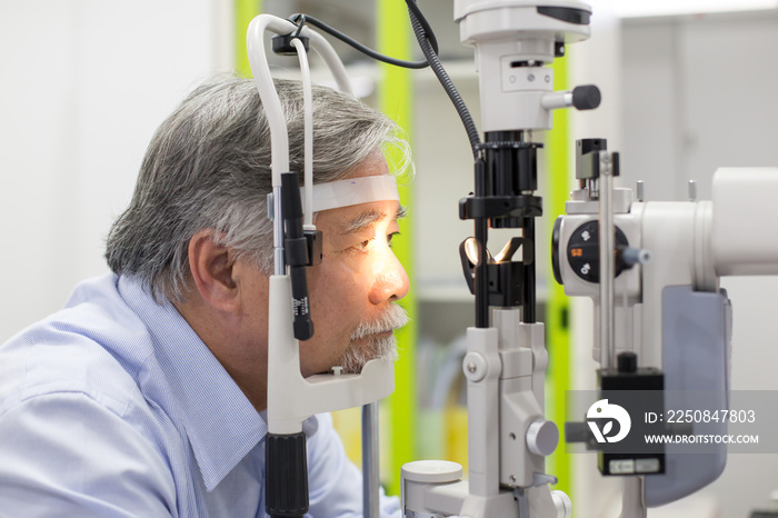 Asian senior male patient having him eyes examined by laser machine. Doctoroptometry concept.