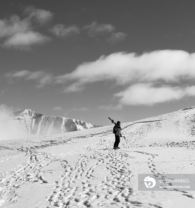 Skier with skis on his shoulder and snowy mountain