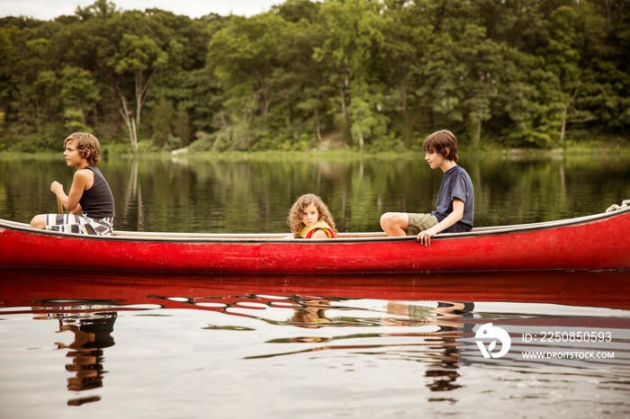 Boys (12-13, 8-9) and girl (4-5) in red boat forest in background