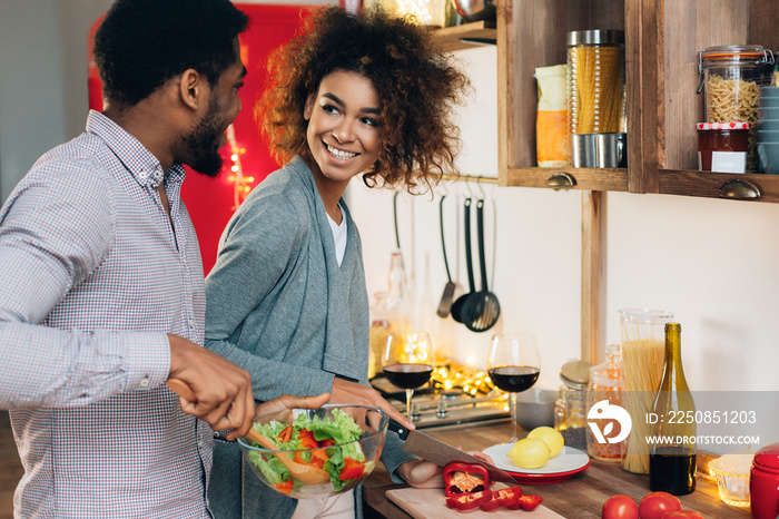 Vegetarian african-american couple cooking salad in kitchen