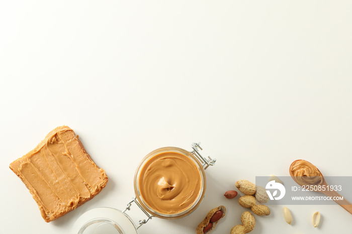 Flat lay composition with peanut butter sandwich, glass jar, peanut and spoon on white background, s