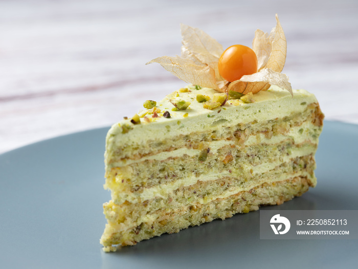 close up view to pistachio cake with physalis on gray plate with copy space