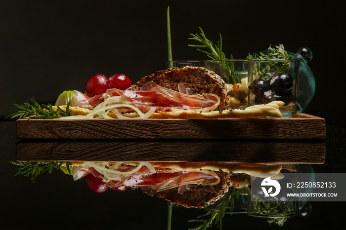 Traditional Italian appetizer board with prosciutto, bread and condiments. Exquisite dish. Creative 