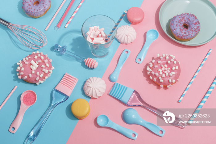 Kitchen utensils and tools, pastries and sweets on a pink and blue background. Top view. Copy space.