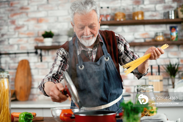 Man in kitchen. Old man cooking pasta.