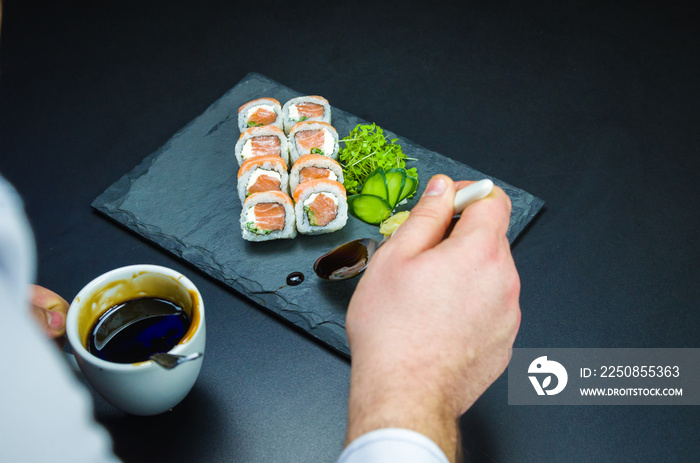 Sushiman在盘子里加入去皮酱。寿司，传统的日本料理。美味的Uramaki