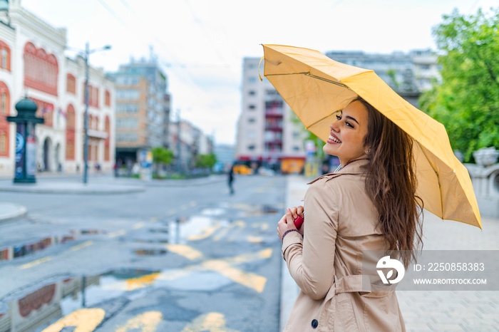 Woman in autumn city. Woman walking on rainy day with yellow umbrella. A portrait of a Long-haired s