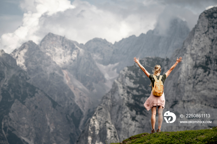 Woman standing at the top of the hill in mountains looking at wonderful scenery. Triglav, the highes