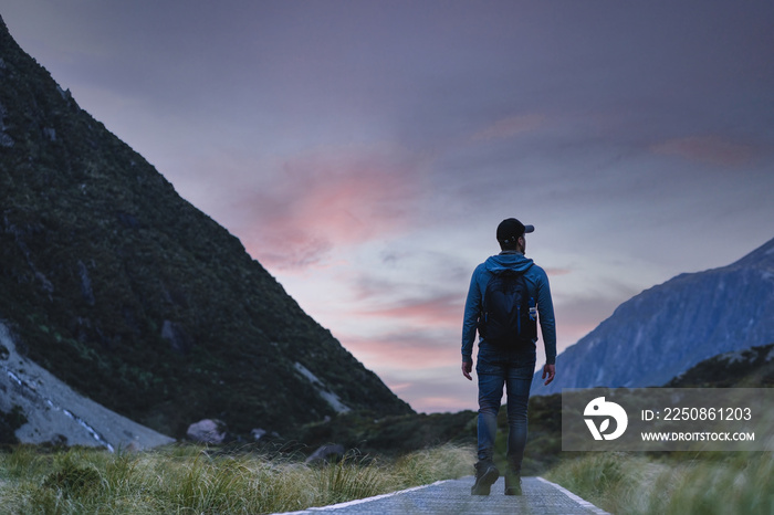 Man walking among the mountains in a national park during sunset. Hooker Valley track, New Zealand