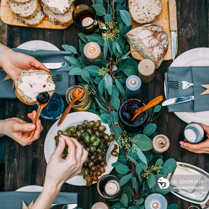 Top view over a dining table, decorated with eucalyptus leaves, with tableware and food. Backyard pi