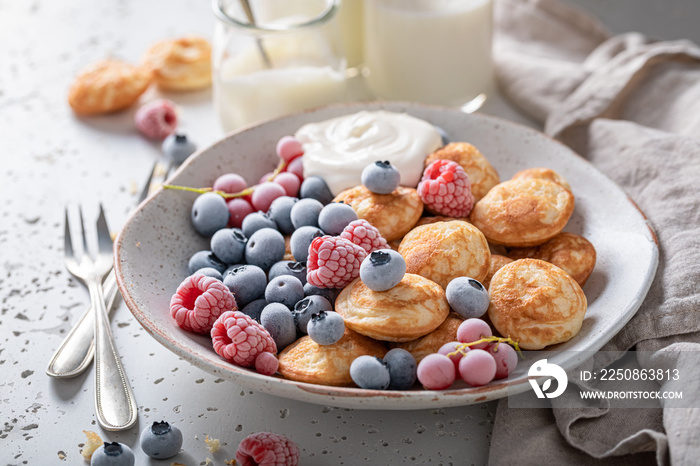 Delicious poffertjes with frozen blueberries and raspberries.