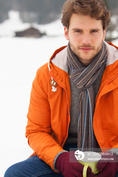 Portrait handsome young man drinking coffee in snow