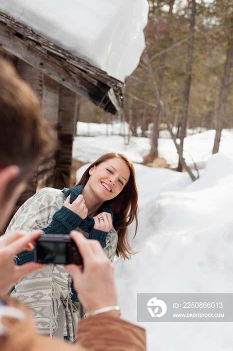 幸福的女人在雪地小屋外摆姿势拍照