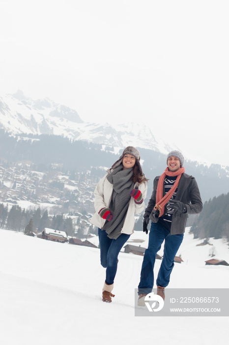 Happy couple couple running in snowy mountain field