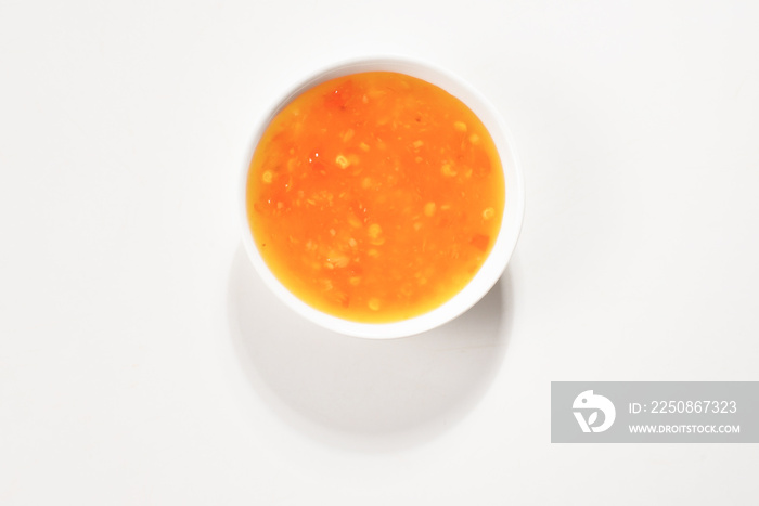 Orange sauce in white plate on white background.